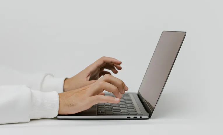 Close-up of hands typing on a laptop keyboard checking written text