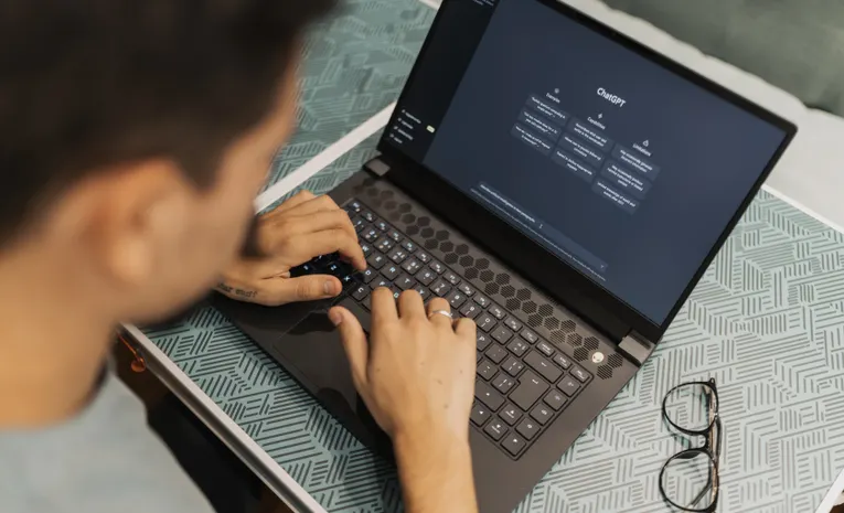 Man typing prompts into an AI chatbot on a laptop
