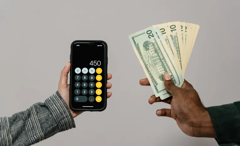 Hands using a calculator and smartphone representing cloud cost optimization